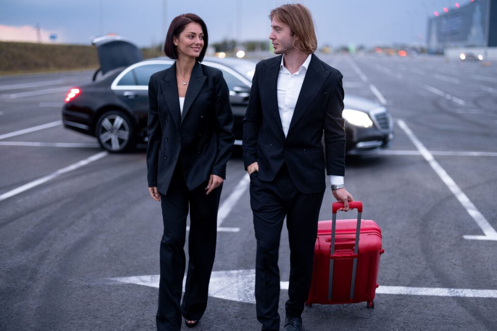 Professional man and woman in business attire strolling with a suitcase.