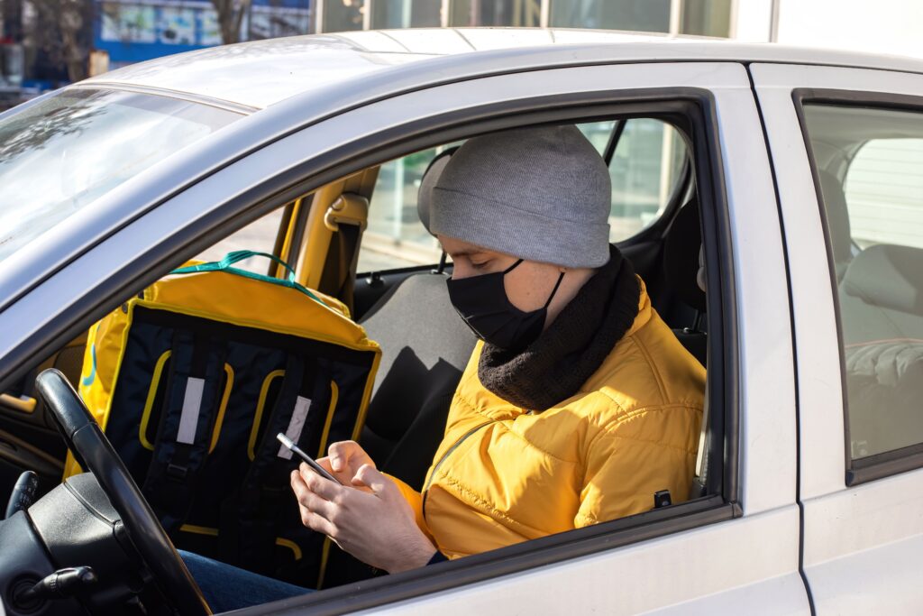 A man holding a cell phone in a car, browsing the internet.