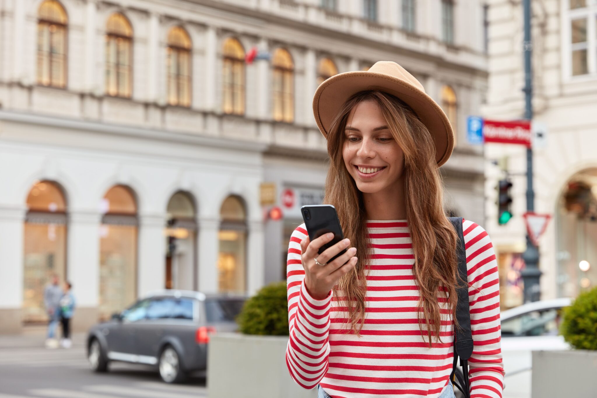 Woman in hat and striped shirt looking at her phone.