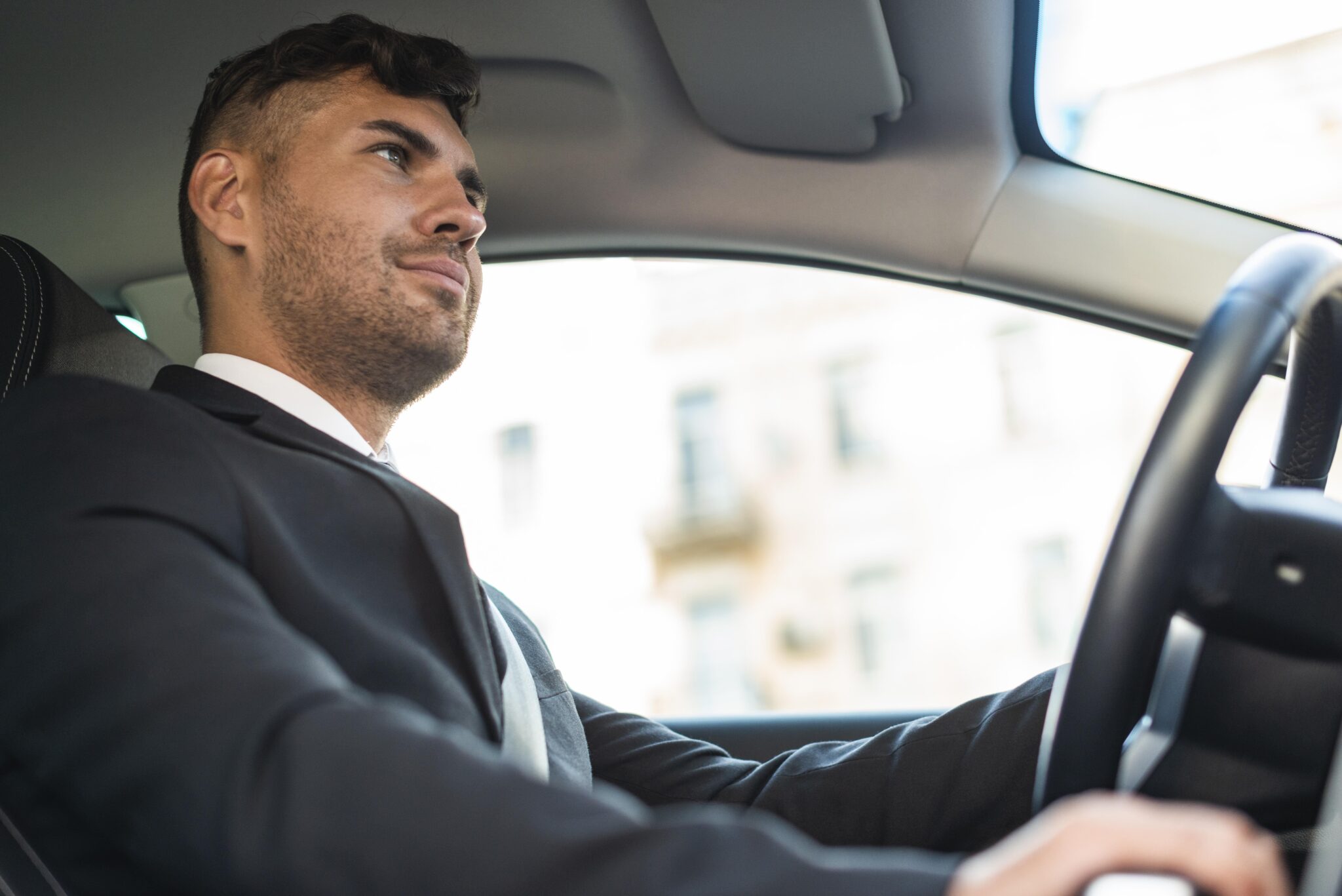 Businessman in suit behind the wheel of a car.